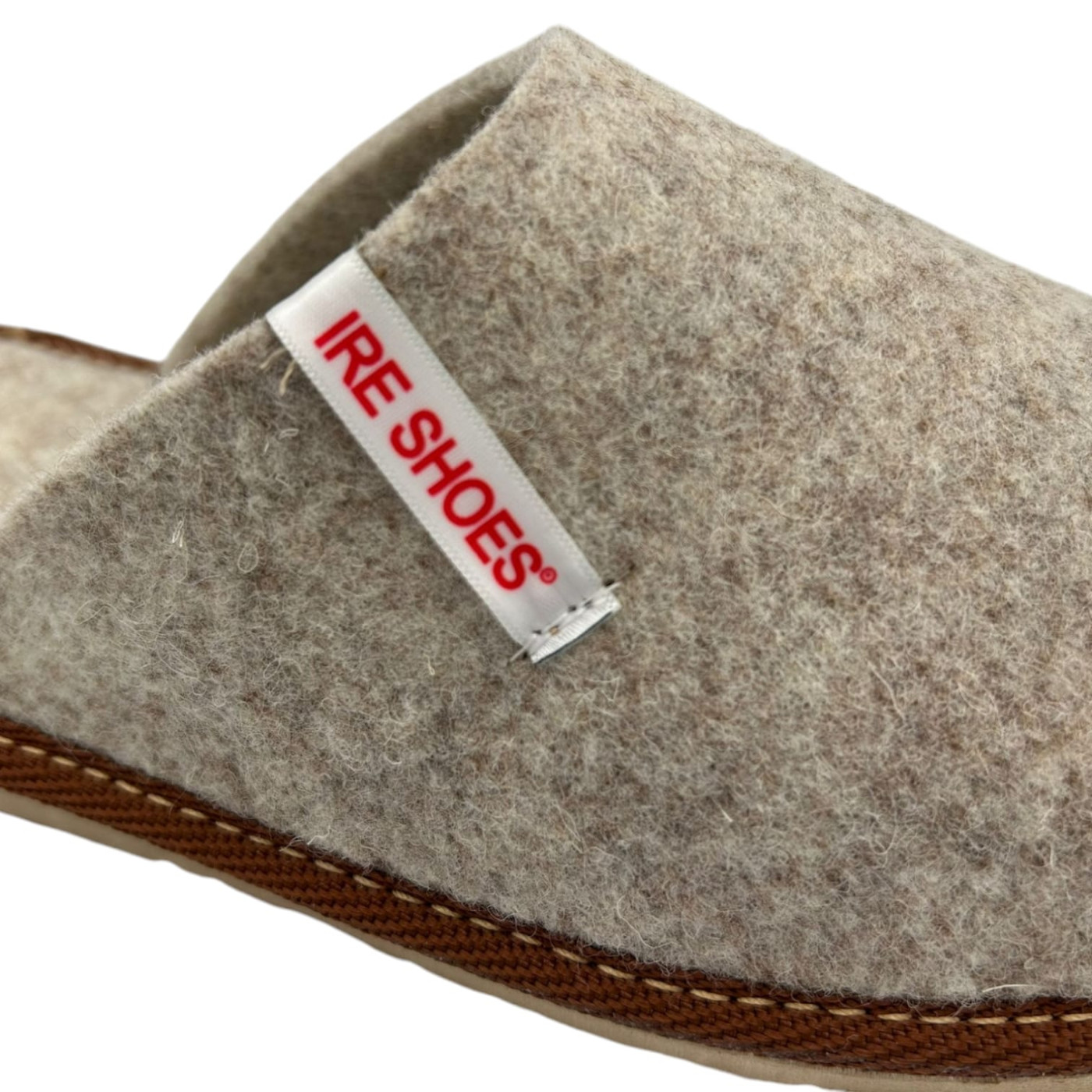 Zbliżenie filcu, metki IRE SHOES i brązowej lamówki kapcia KFM24-220