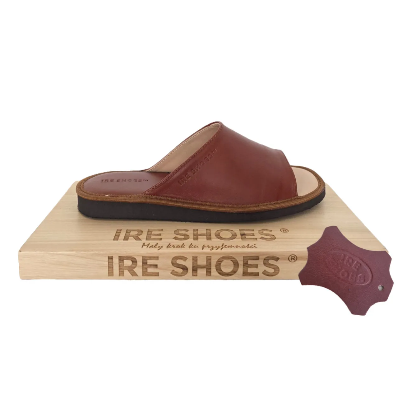 Brązowy klapek z odkrytymi palcami na drewnianej podstawce IRE SHOES, obok próbka materiału