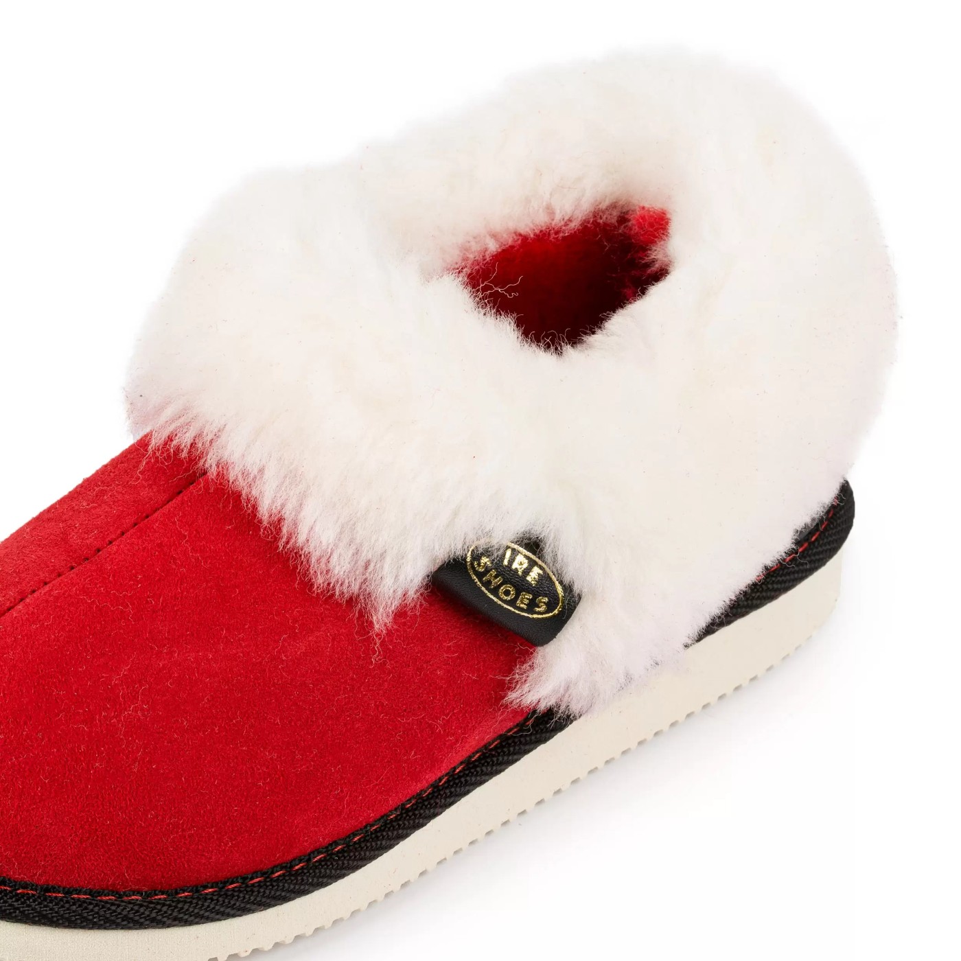 Zbliżenie jasnego kołnierza i czarnej metki IRE SHOES na czerwonym bamboszu