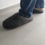 Kapcie KWM25-256 na stopach z jeansami, na szarej podłodze