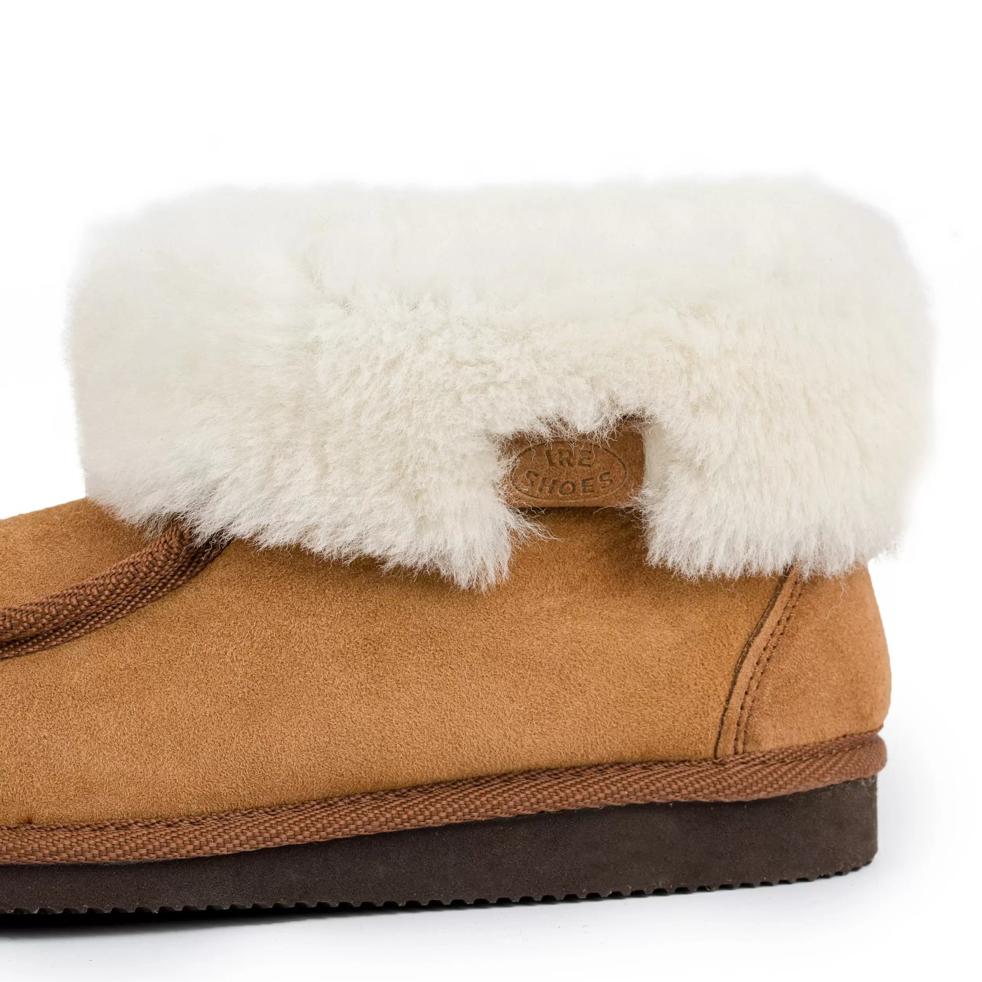 Zbliżenie jasnego kołnierza, metki IRE SHOES i szwu przy pięcie